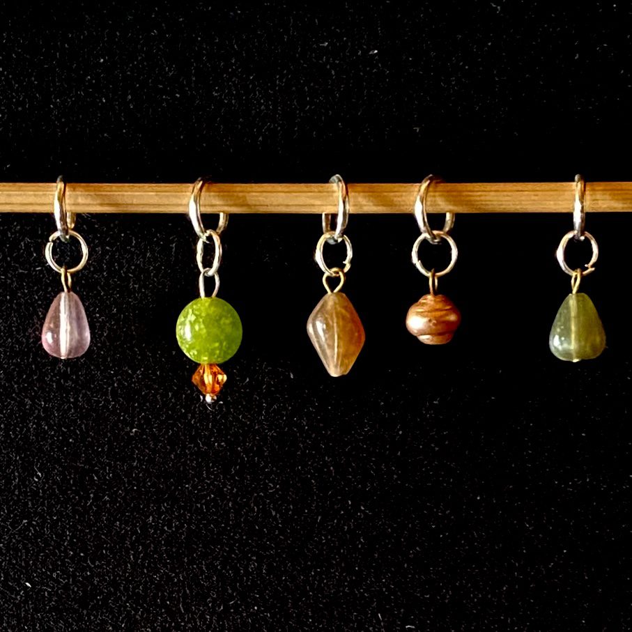 Five stitch markers made from repurposed antique beads. All are a different colour and size.