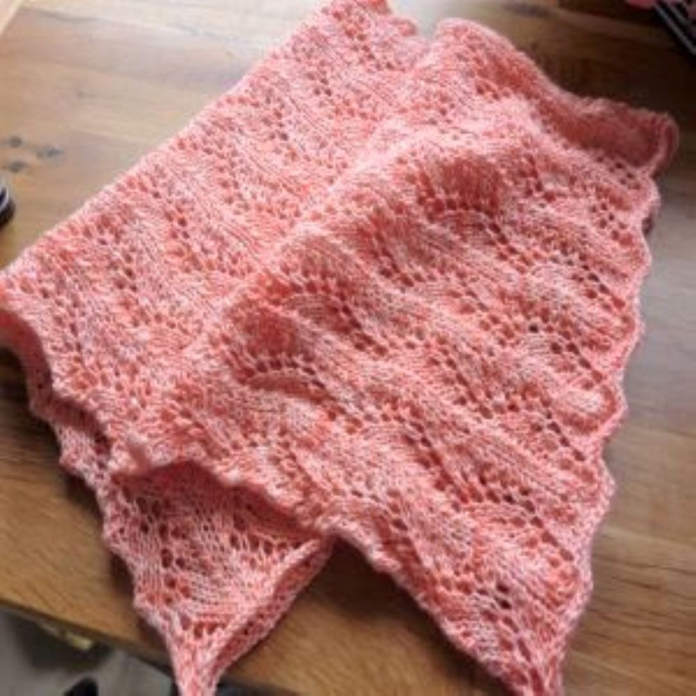 The Hummingbird Cowl knitted in a peach coloured wool. I folded the cowl over at an angle to show the lace pattern clearly.