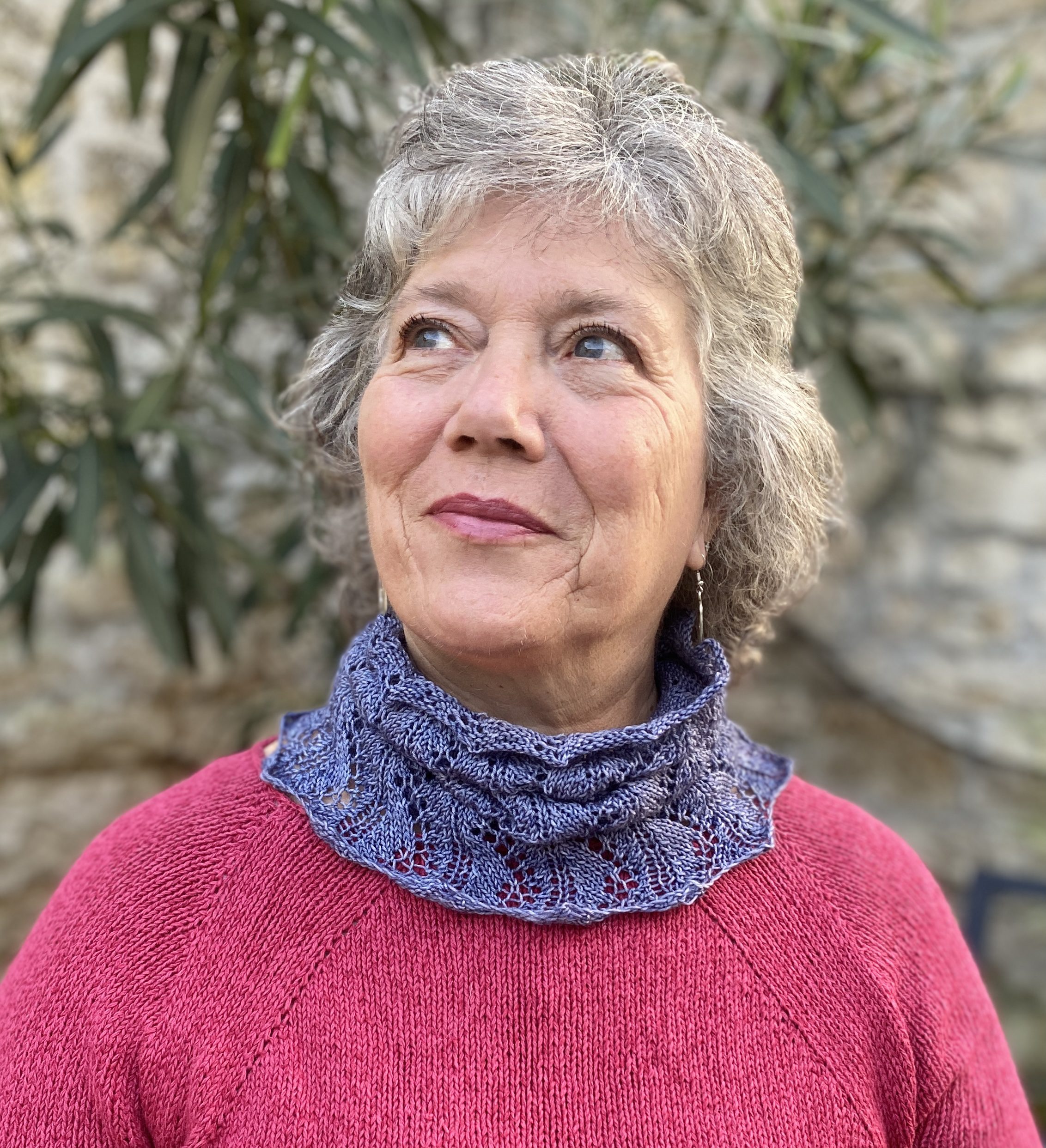 Older woman wearing a lacy cowl knitted in grey Merino wool.