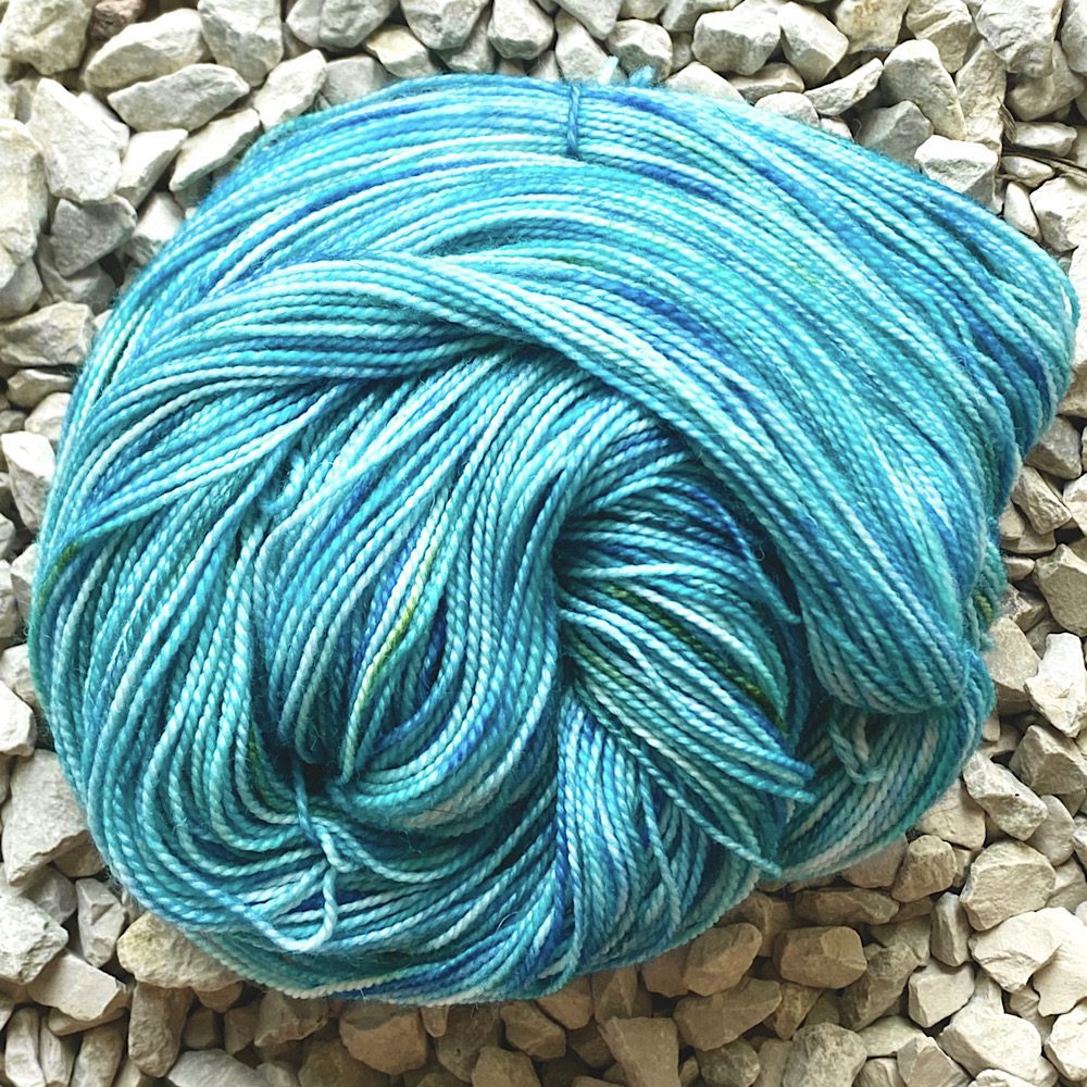 4 Ply Merino Nylon yarn, arranged in a swirl to show to spun twist of the yarn and the variegated dye method. Colours are: sea blues and delicate greens