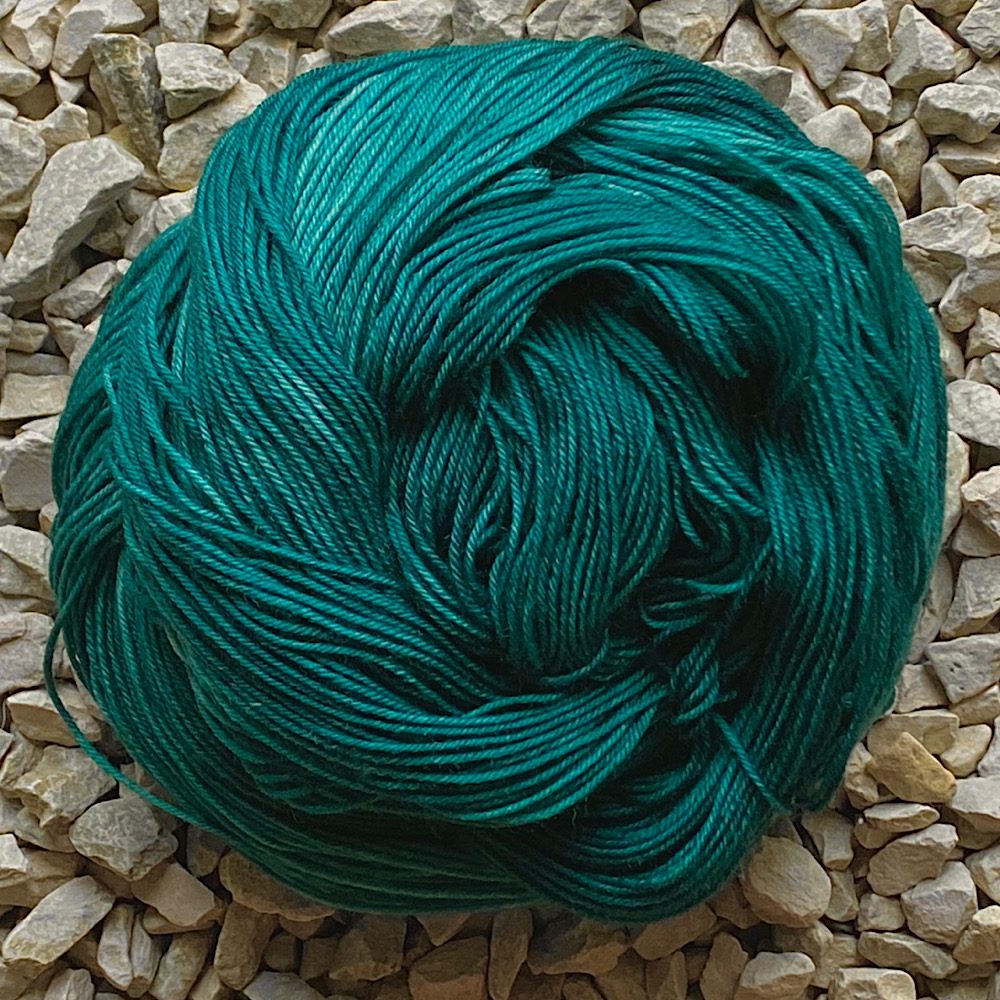4 Ply hand dyed yarn swirlde into a closed circle to show the variations in the jade greens
