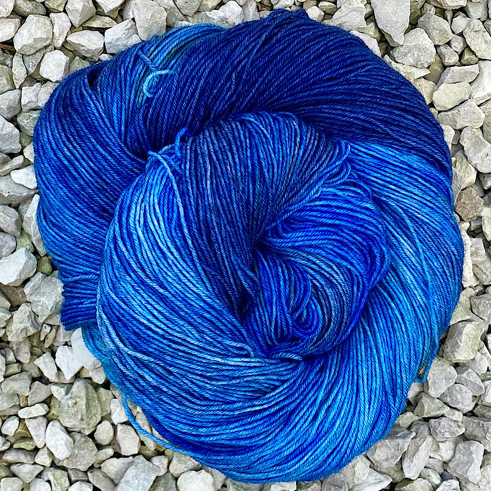 Photo od hand dyed BFL wool swirled into a circle shape on a pebble background