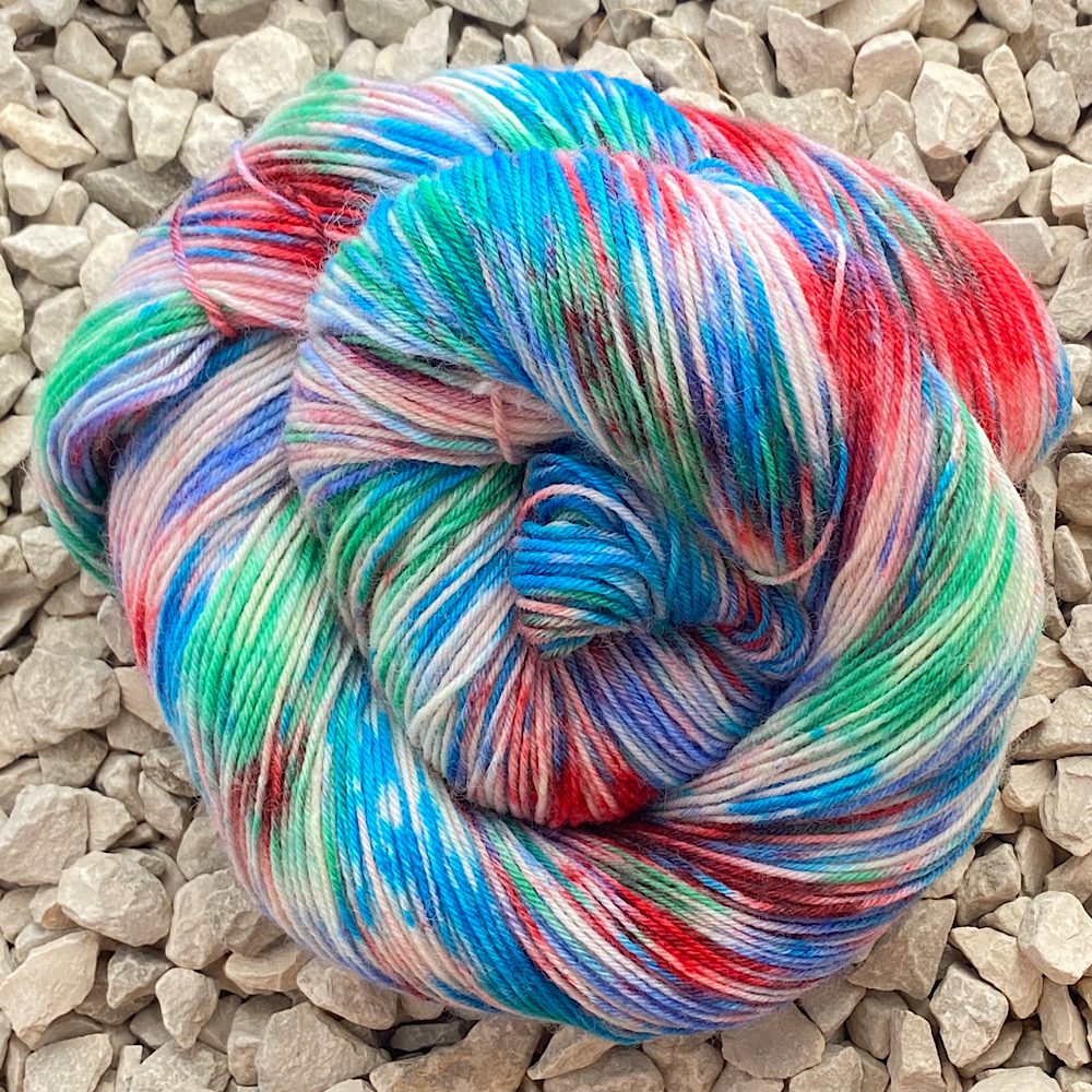 Swirl of yarn skein, splashed with reds, blues and greens on bare wool