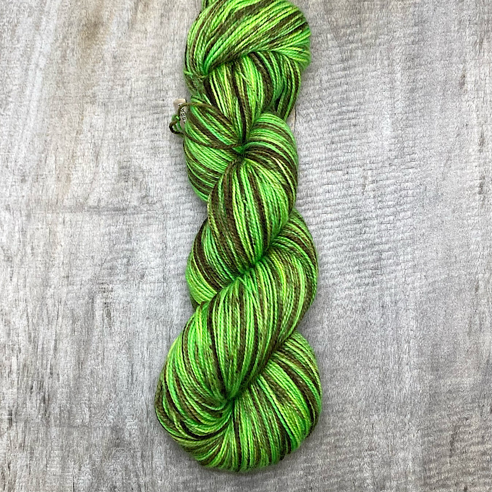The end of a skein of hand dyed pure BFL wool, spun with a twist, in colour 'Chocolate Lime' - a lime coloured background with hand painted sections of brown.