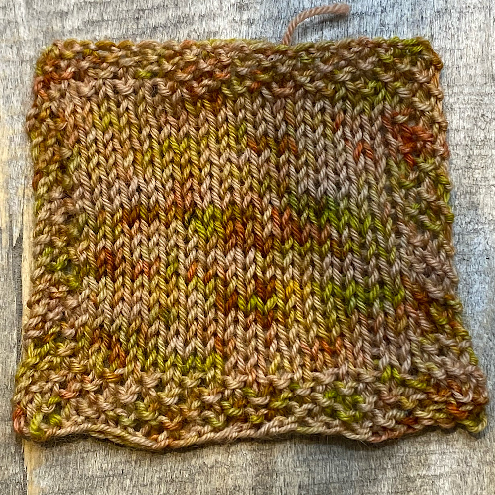 Photograph of a knitted square in hand dyed BFL wool in 'Bradgate Park', Showing the colours and the general look of the dye style when knitted.