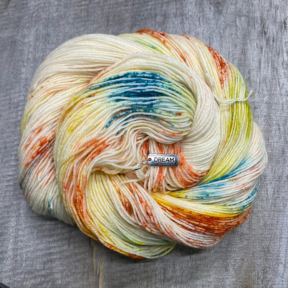 Photograph of hand dyed BFL wool in 'Copper Verdigris', arranged in a swirl. The colours are a mix of copper colours and the Verdigris patterning of outdoor copper.