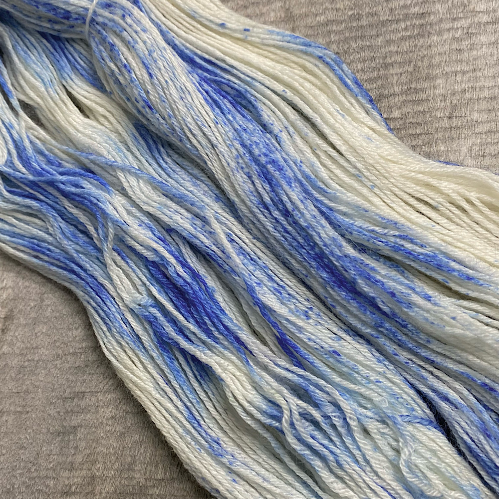 Photograph of hand dyed BFL wool in 'Sailor Moon', arranged in flat. The blue is sprinkled on the bare wool in powder form.