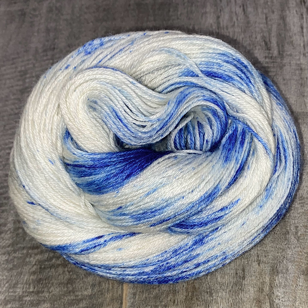 Photograph of hand dyed BFL wool in 'Sailor Moon', arranged in a swirl. The blue is sprinkled on the bare wool in powder form.