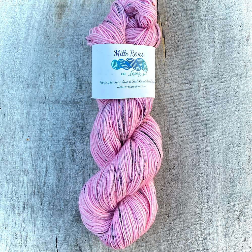 A skein of hand dyed wool in pink with grey speckles
