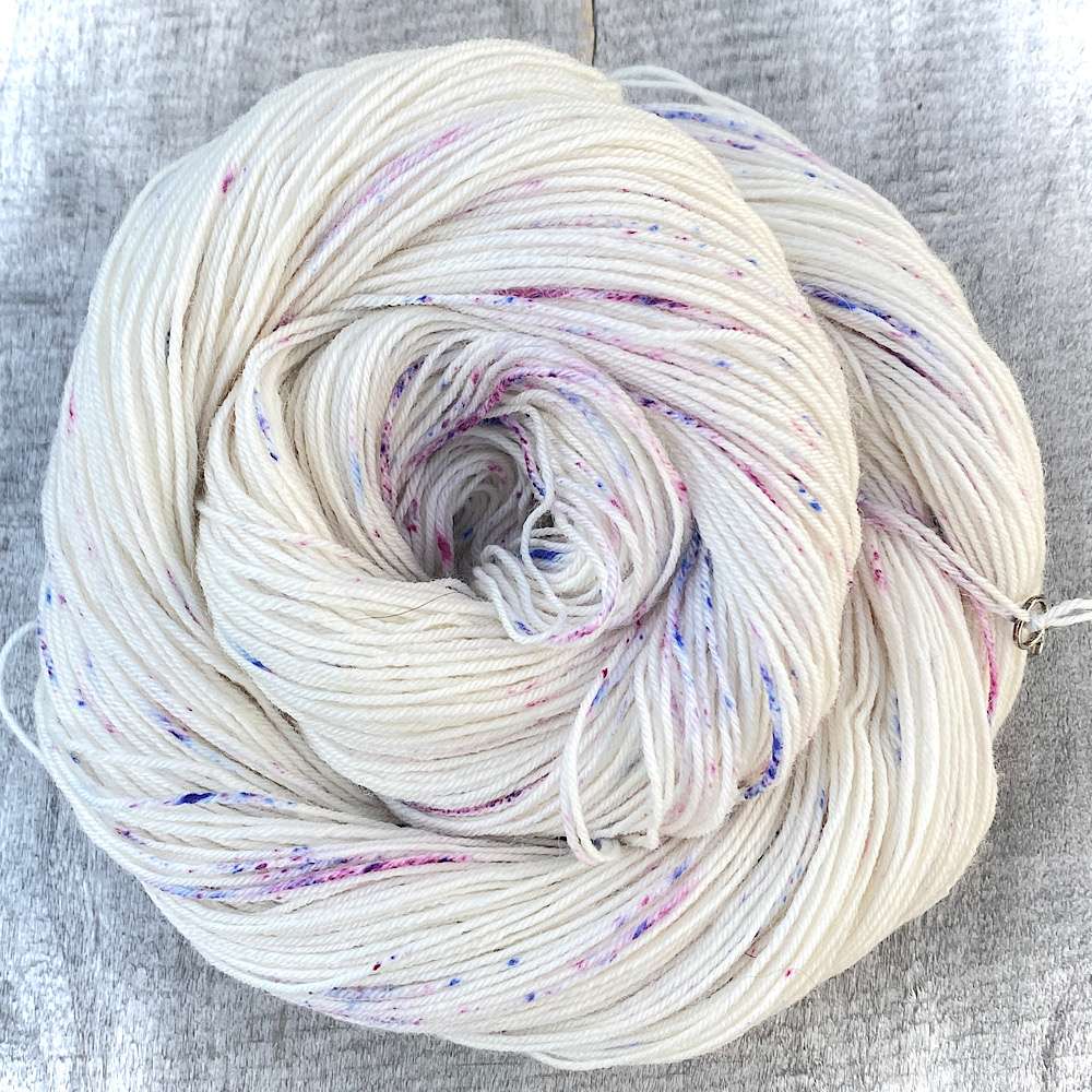 A swirl of undyed BFL wool with blue and pink speckles