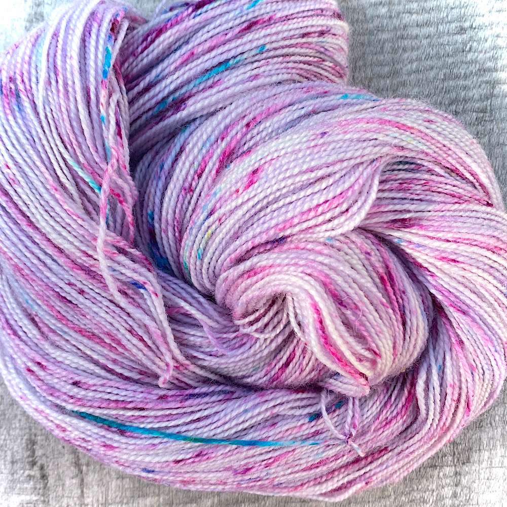 BFL wool hand dyed in a subtle lilac toned pink, then speckles with deep pink and a few turquoise strands
